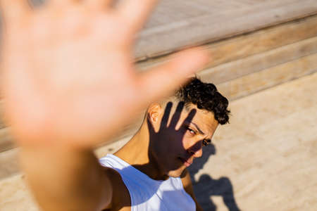 mixed race man hiding from the sun at sunny day outdoorsの写真素材