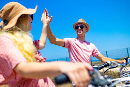 Happy adult people cheerful couple enjoy the outdoor leisure activity riding a bike seasideの写真素材