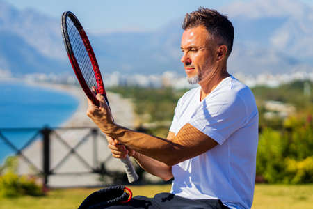 man holding tennis racket outdoors at sunny dayの写真素材