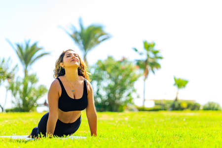 Yoga outdoors - woman doing yoga in summer green park at sunny day