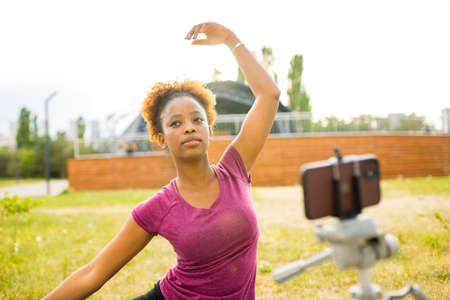 happy mexican woman sport blogger with camera on tripod recording outdoor fitness trainingの写真素材