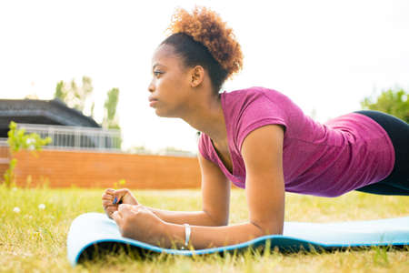 hispanic woman blogger in sportswear shoots video on camera phone as she does yoga on mat in summer...