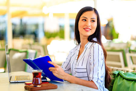 Image of happy asian woman using laptop while sitting at cafeの写真素材