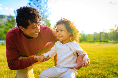multicultural race enjoy father carrying little african girl child smiling in summer park