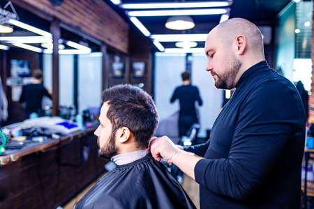 Hairstylist cutting hair of male customer at barber shopの写真素材