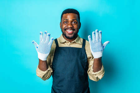 african american man in black apron is ready to spring season in blue studio backgroundの写真素材