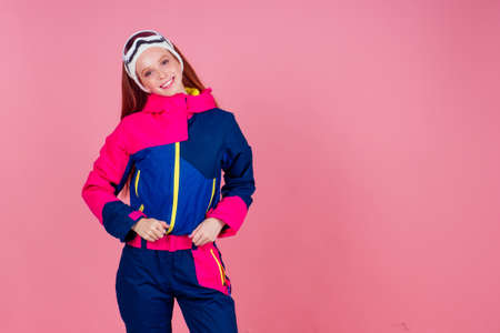 Portrait of sexy smiling redhaired ginger woman in warm clothes professional skier in studio pink...