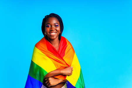 brazilian woman in multi color top blouse rainbow and make up in blue studio background