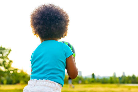 cheerful girl with afro curly hair playing with green ball like a watermelon outdoorsの写真素材
