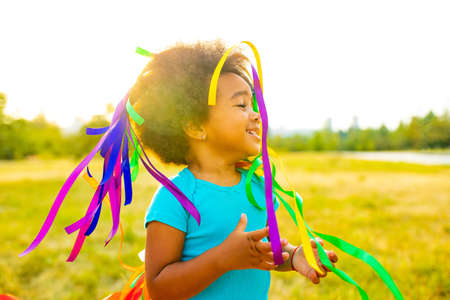 multicultural little girl with curly afro hair making a gift for parent by herself outdoor shotの写真素材