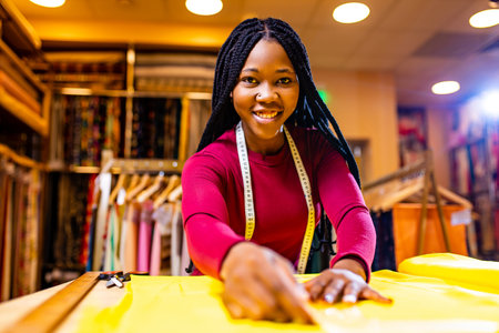 tanzanian woman with snake print turban over hear working in fabrics shopの写真素材