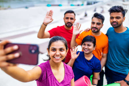 four indian people warming up outdoors in sport wear making selfie on smartphone camera