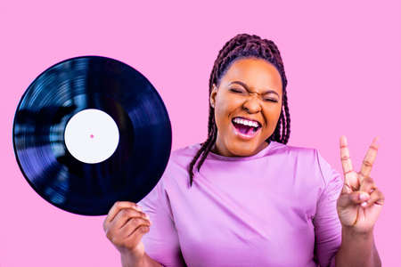 hipster lady with cool dreadlocks pigtails showing old fashion school vinyl in pink studio backgroundの写真素材