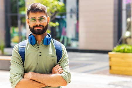 indian student with blue headset and backpack well looking at sunny dayの写真素材