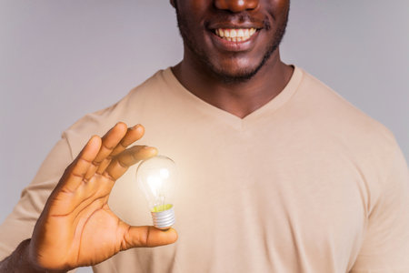 latin brazilian man holding a lightbulb in hands concept of idea and creativityの写真素材