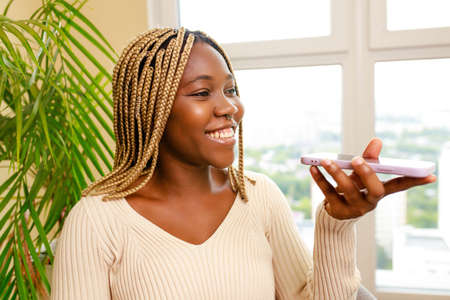 african american woman recording a voice message by mobile with friend