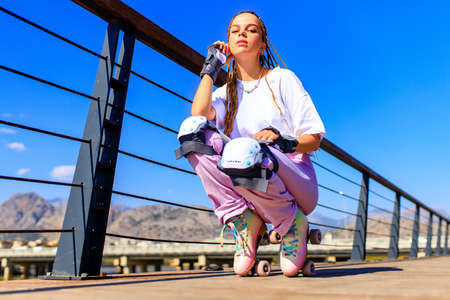 Happy woman with long blonde braids hair on the roller-skate in the park beach and mountain backgroundの写真素材