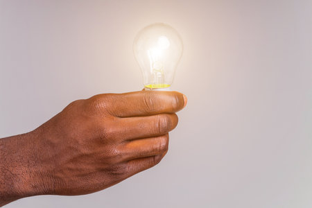 latin brazilian man holding a lightbulb in hands concept of idea and creativityの写真素材