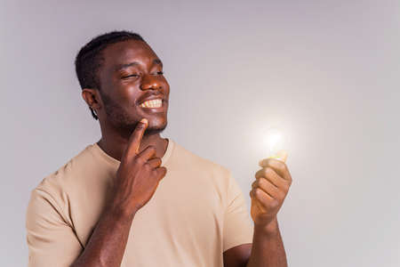 latin brazilian man holding a lightbulb in hands concept of idea and creativityの写真素材