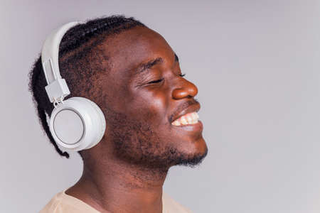 mexican man with white headphone listening music in beige t-shirtの写真素材