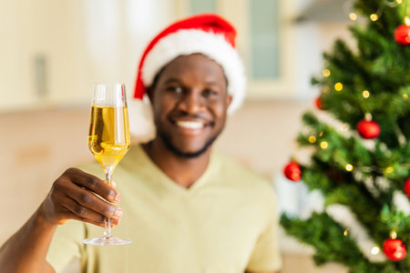 afro american man raised a glass of champagne and makes a toast at homeの写真素材