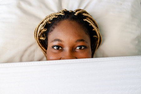 latin hispanic woman hide behind the blanket in the morning at homeの写真素材
