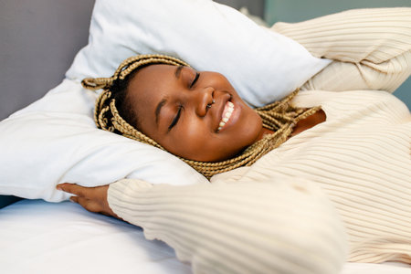 Afro american female keeping eyes closed while awake at the bedroomの写真素材