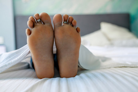 Close up of female feet in bed in bedroom under blanketの写真素材