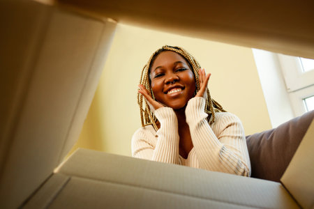 happy african american woman looking inside of box and surprised of cute petの写真素材