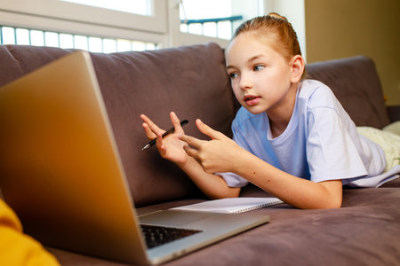 blonge hair little girl using a laptop,doing homework at home.Back to school concept