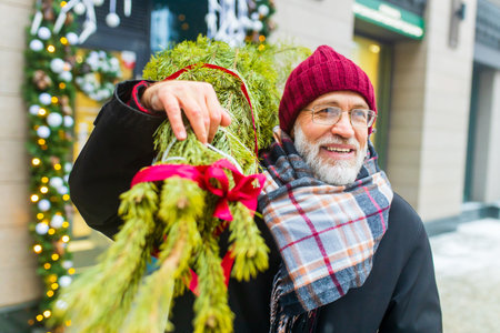 happy retired man walking by street with christmas tree to home from marketの写真素材
