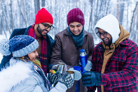 Happy young indian friends get warming with hot teaの写真素材
