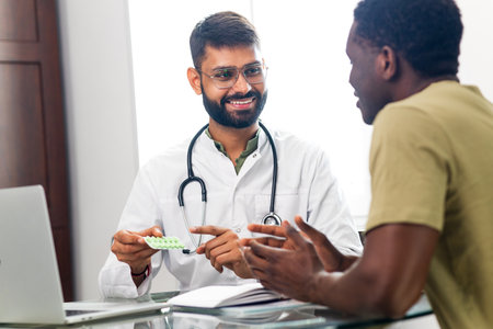 Indian doctor therapist in white coat consulting supporting patient in modern clinic hospitalの写真素材