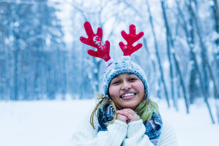 Happy indian woman having fun and enjoying first snow wear fun hat deer hornの写真素材