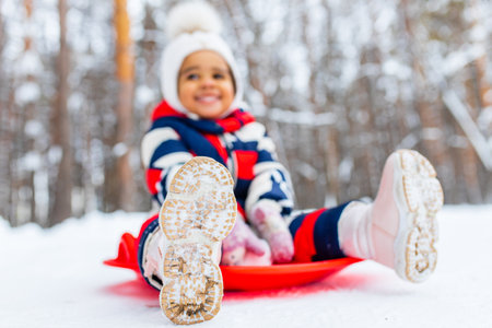 little girl having fun and sledding sled playing in snowy parkの写真素材