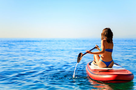 Woman paddling on sup board with mountains on backgroundの写真素材