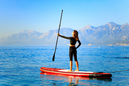 Woman paddling on sup board with mountains on background
