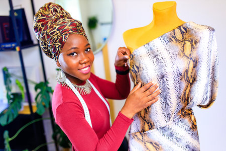 tanzanian woman with snake print turban over hear working in dressmaking shopの写真素材