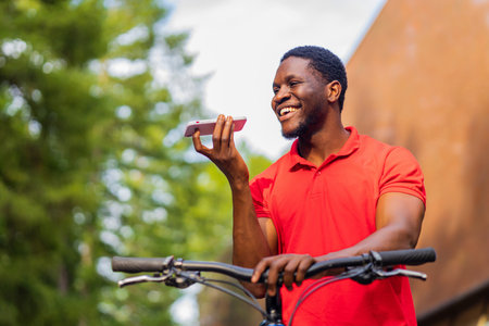 latin amerixan man in casual clothes smiling while leaning on his bikeの写真素材