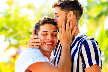 Happy gay couple spending time together in sunny day in green parkの写真素材