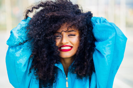 multicultural race woman with curl hair in blue windbreaker outdoorの写真素材