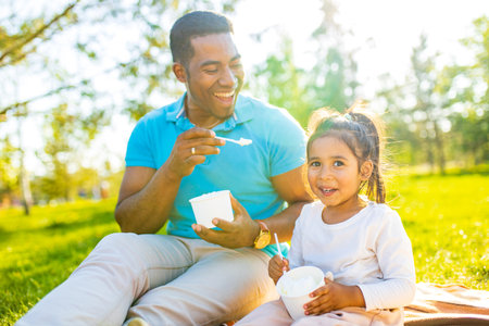 fathers day celebration happy afro american man with his cute baby in summer park having fun togetherの写真素材