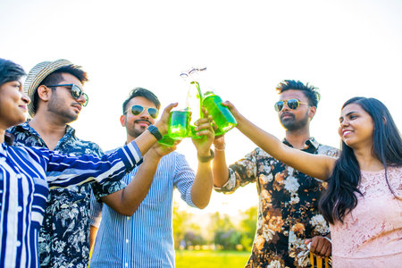 pakistanian happy best friends partying with lemonade and beer in summer parkの写真素材