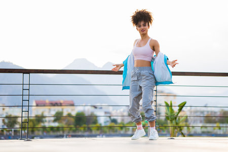 Urban happy afro woman in sports outfit dancing outdoorsの写真素材