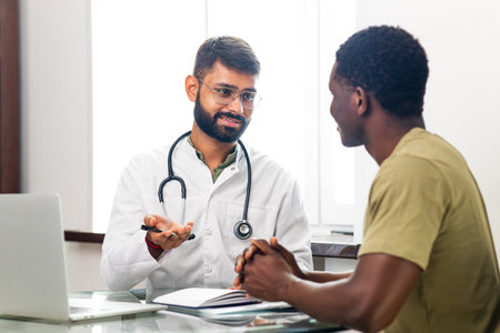 Indian doctor therapist in white coat consulting supporting patient in modern clinic hospitalの写真素材