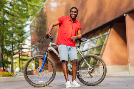 Portrait of handsome smiling stylish hipster with bike in parkの写真素材