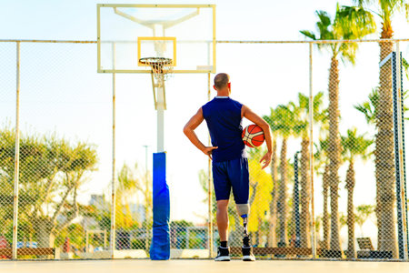 sporty handicapped man in sportswear and with artificial leg basketball player at sunsetの写真素材