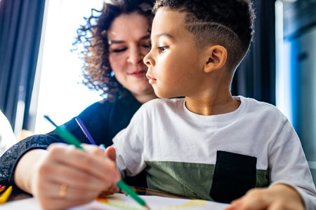 authentic afro hair curly woman and baby boy are painting draw on table day light backgroundの写真素材