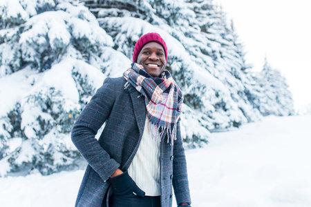 african american handsom man in red hat and stylish plaid coat look at camera with toothy snow- white smile outdoor in parkの写真素材
