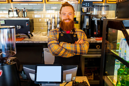 Professional barista young redhaired ginger bearded man in black apron working in coffee shop